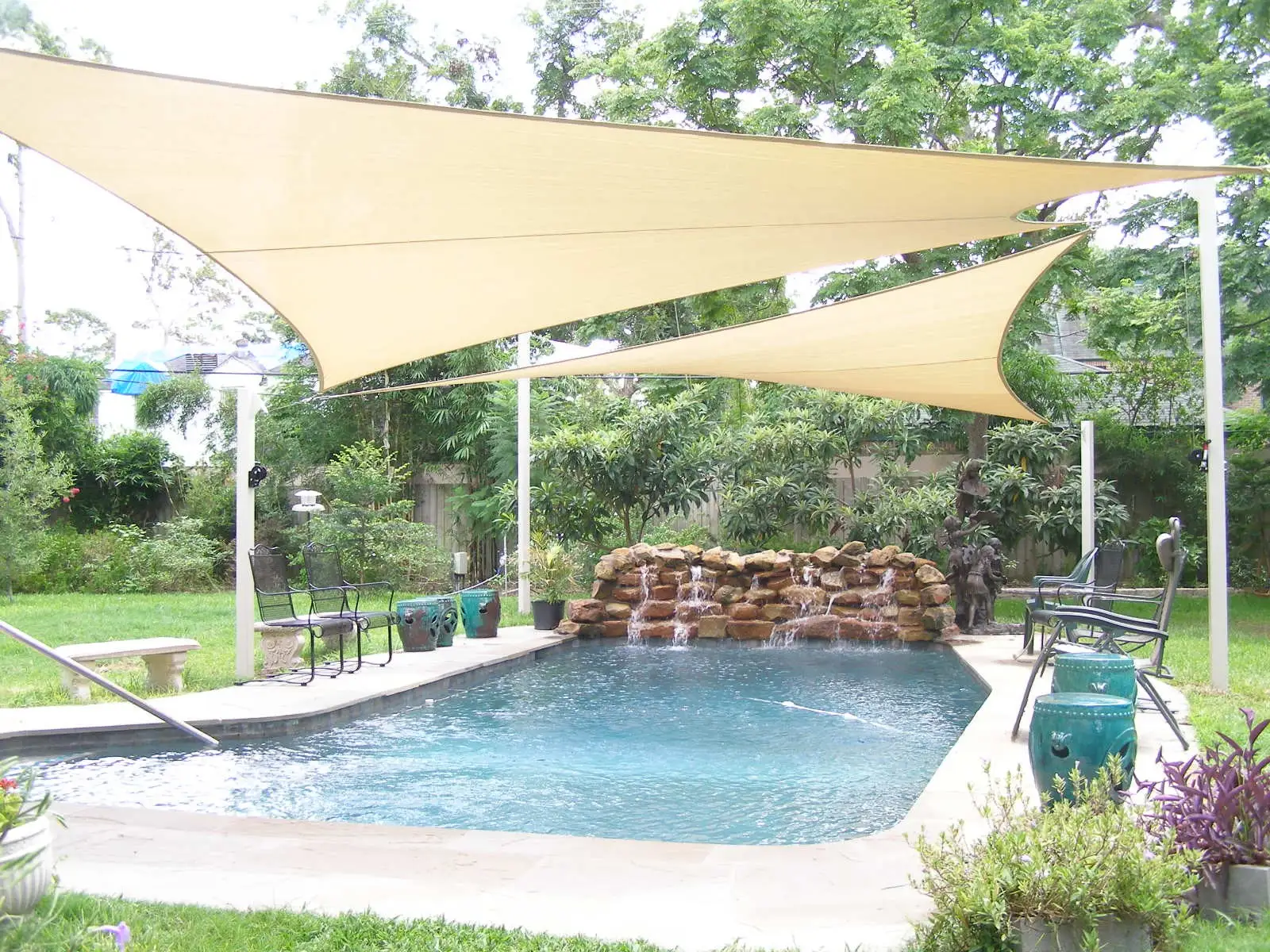 Cream triangular shade sails over a residential pool